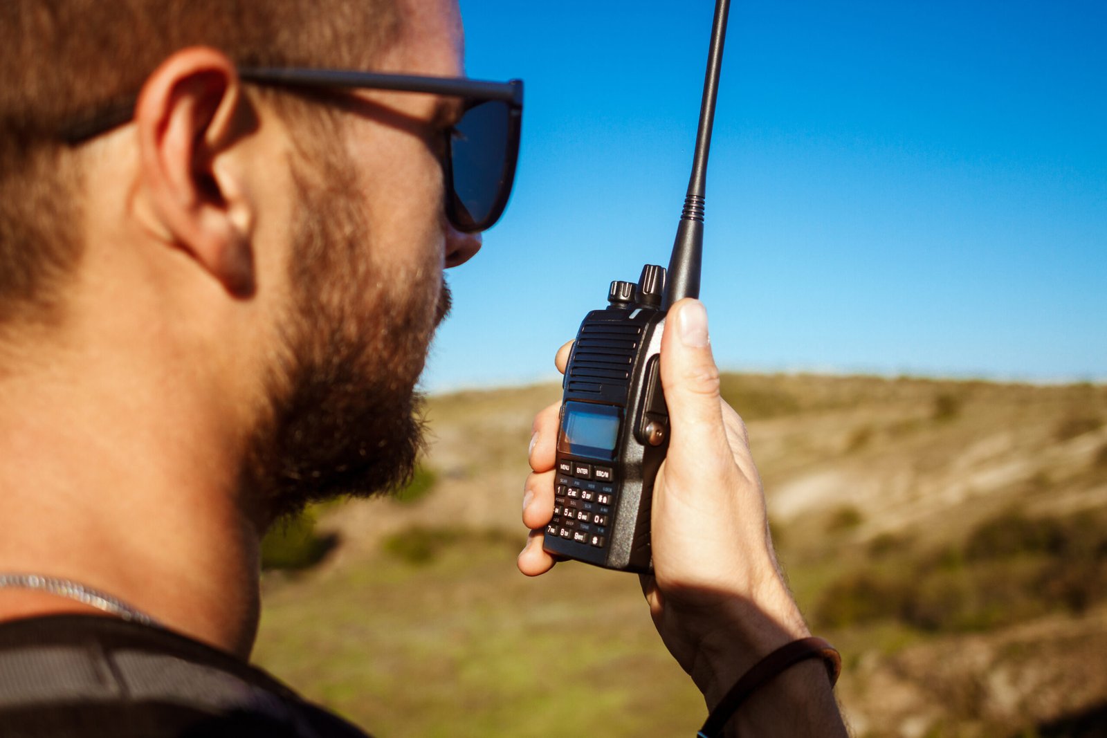 Young handsome man talking on walkie talkie radio, enjoying canyon view. Copy space.